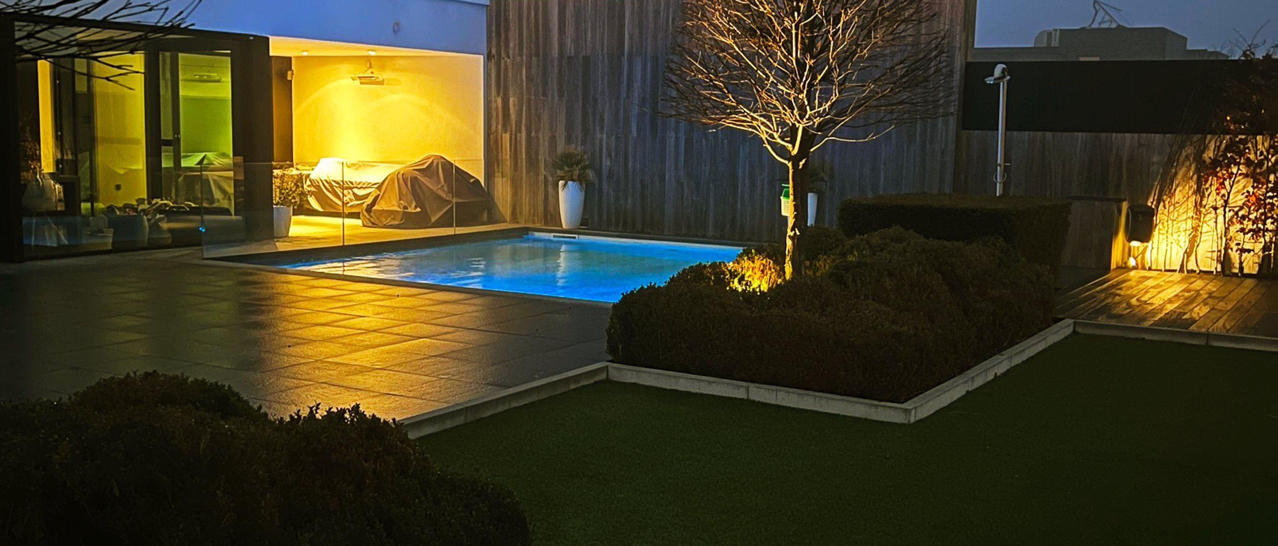 verlichte tuin met zwembad bij schemering