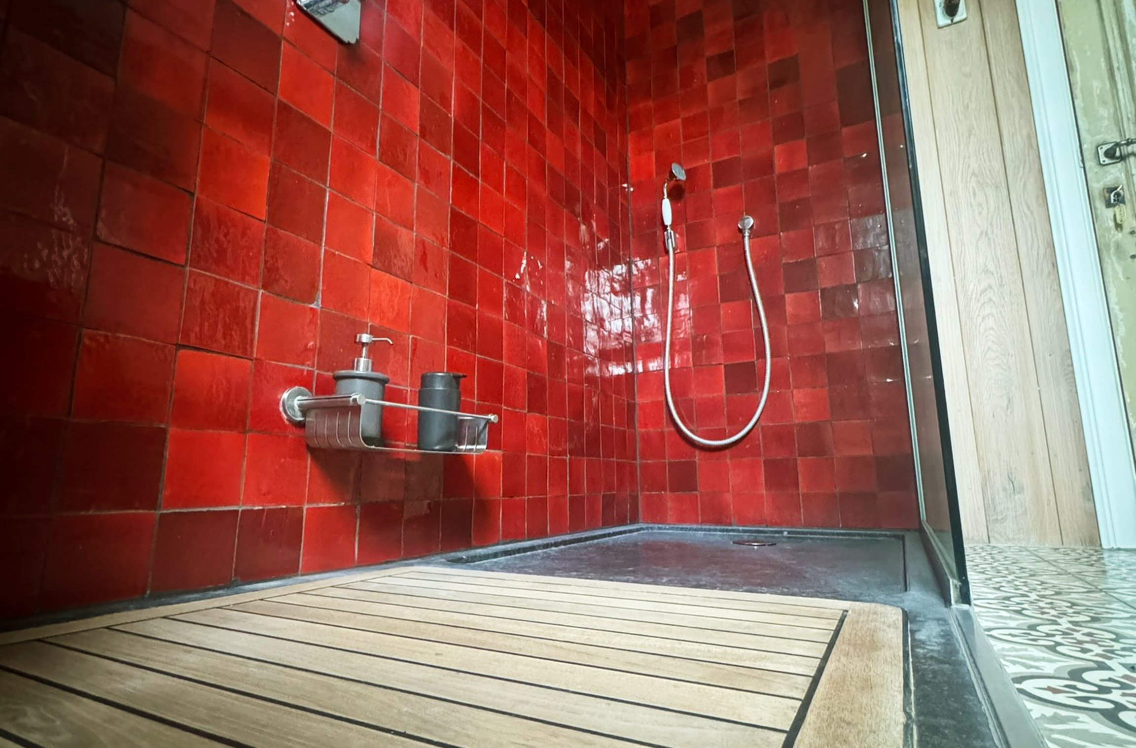 douche met rode tegelwand en houten vloer