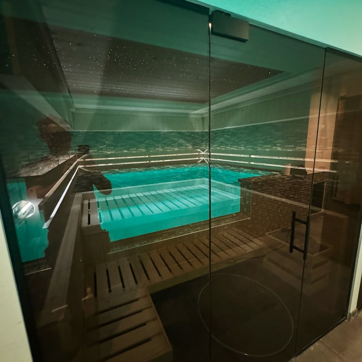 luxe sauna met uitzicht op indoor zwembad en sterrendak