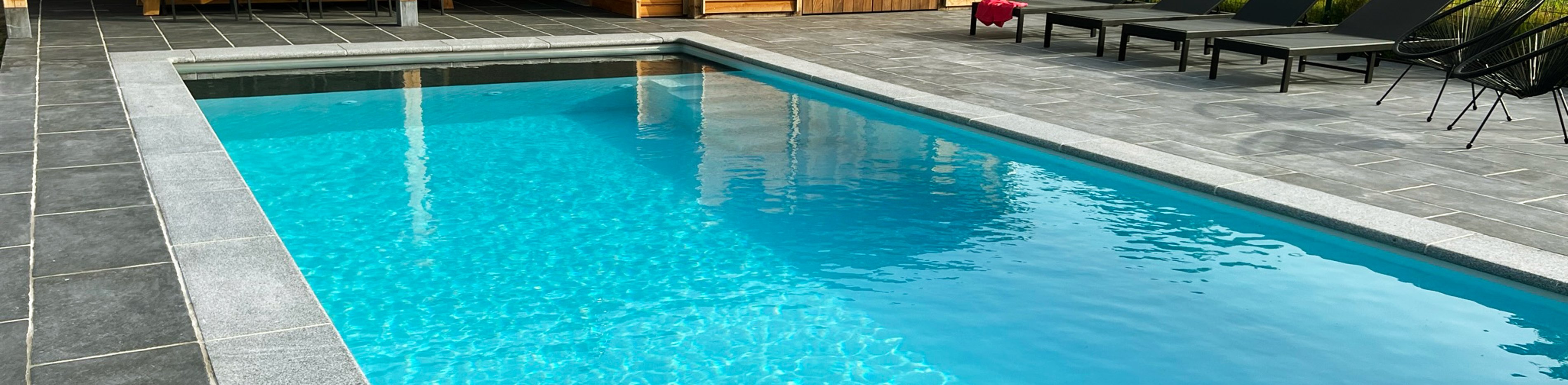 zwembadaanleg met poolhouse en ligstoelen