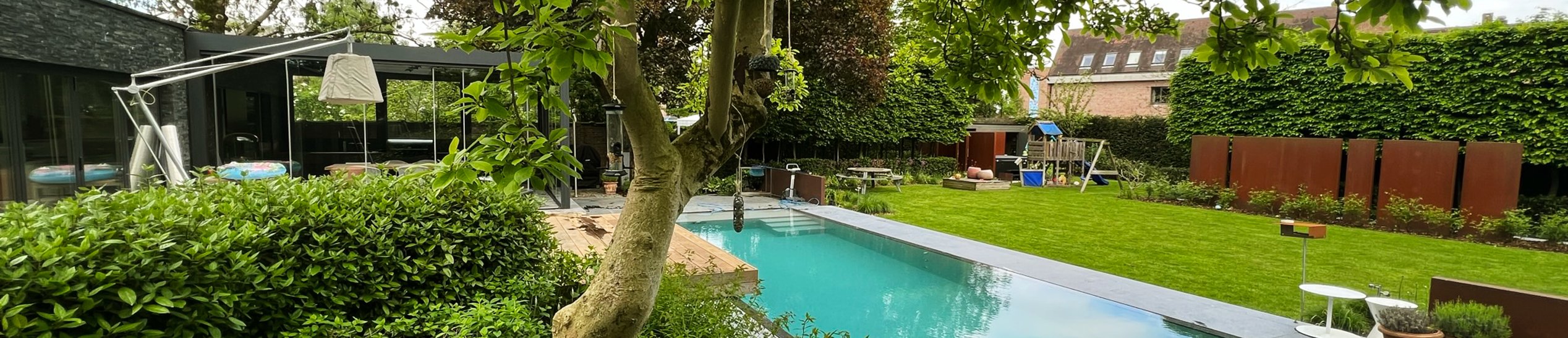 zwembad in tuin met moderne woning en speeltuin