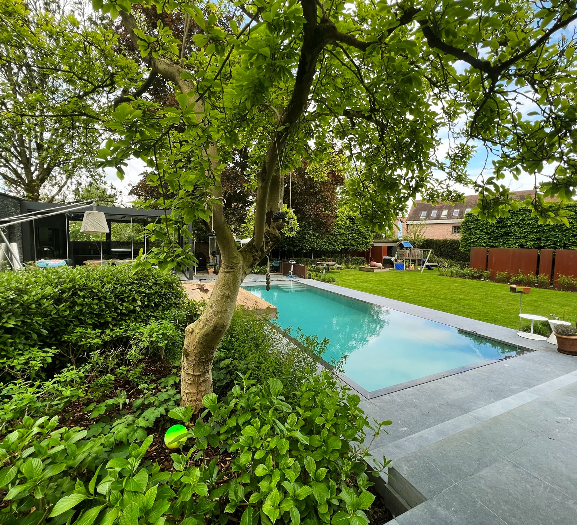 zwembadrenovatie in tuin met moderne woning en speeltuin