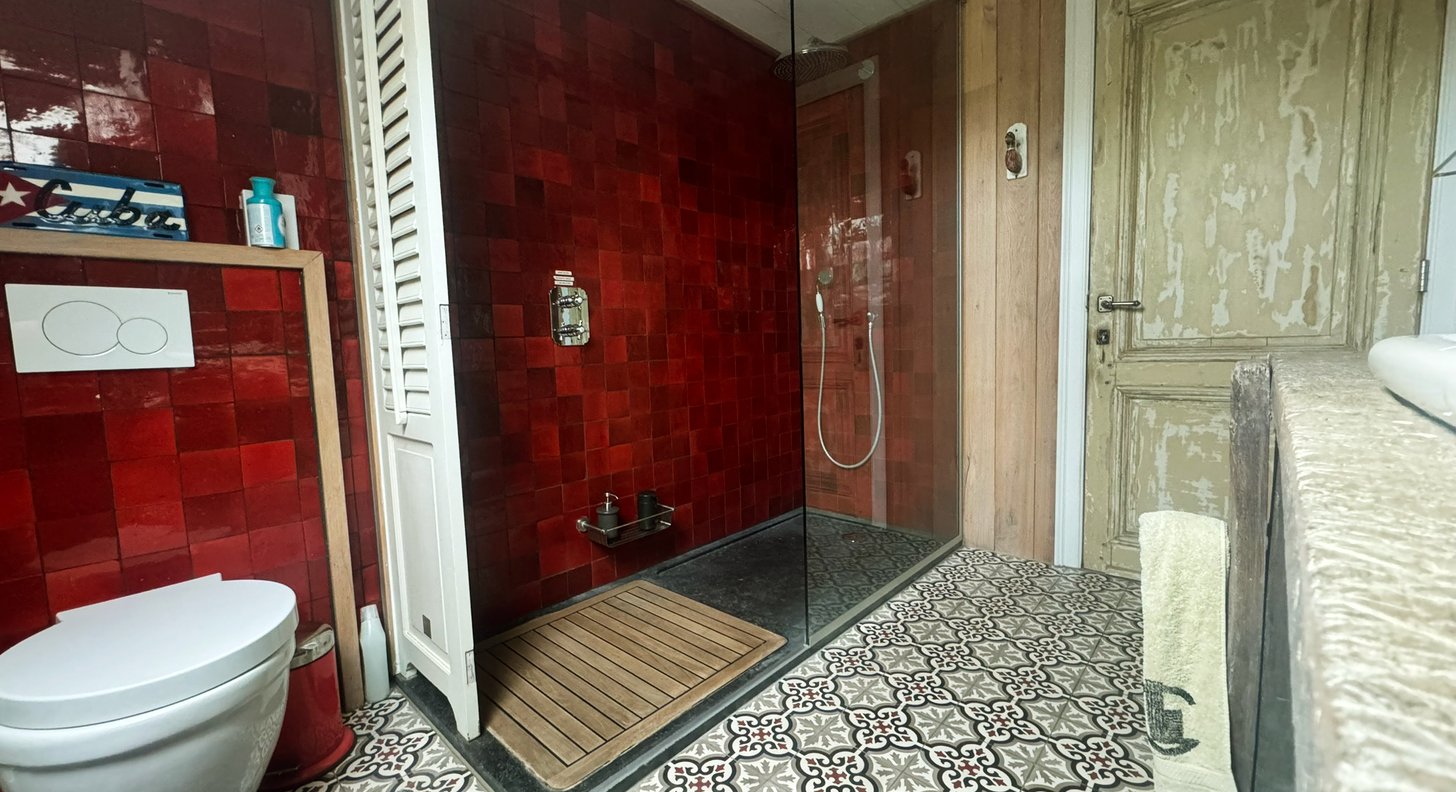 badkamer met rode tegelwand en patroontegels